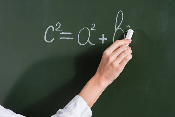 Cropped view of teacher writing equation on chalkboard 