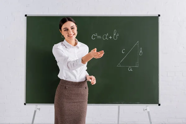 Usmívající Učitel Ukazuje Rukou Tabule Při Hodině Matematiky — Stock fotografie