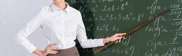 Cropped view of teacher pointing at chalkboard with mathematic equations, banner