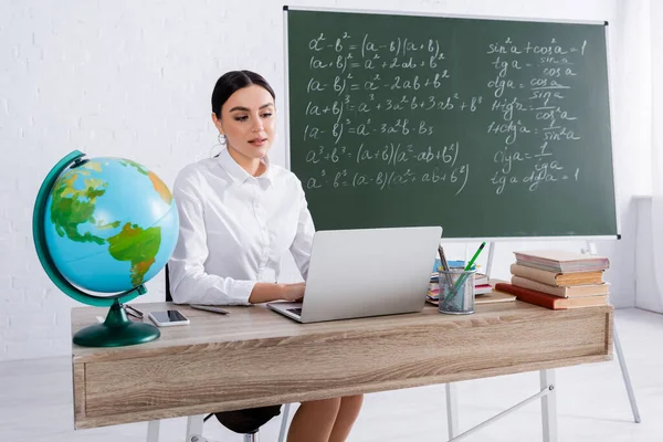 Ung Lärare Använder Laptop Nära Jordklotet Böcker Och Smartphone Klassrummet — Stockfoto