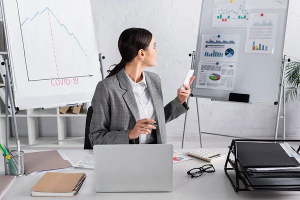 Young Businesswoman Smartphone Looking Flipchart Documents Laptop Office — Stock Photo, Image