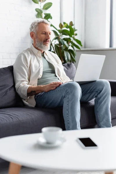 Skäggig Man Med Bärbar Dator Sittande Soffan Nära Kopp Kaffe — Stockfoto