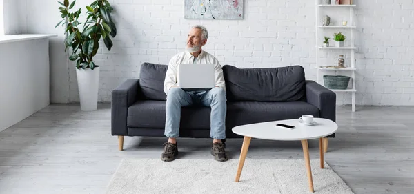 Bearded Man Using Laptop While Sitting Couch Cup Coffee Smartphone — Stock Photo, Image