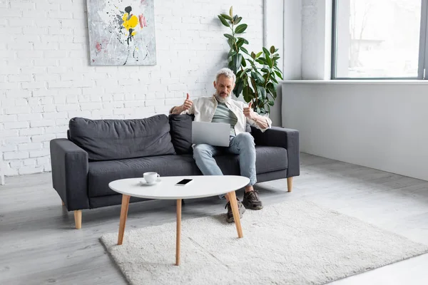 Mann Mit Grauen Haaren Zeigt Bei Videoanruf Auf Laptop Wohnzimmer — Stockfoto