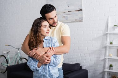 Mutlu çoklu etnik erkek ve kadınlar evde sarılıyor.