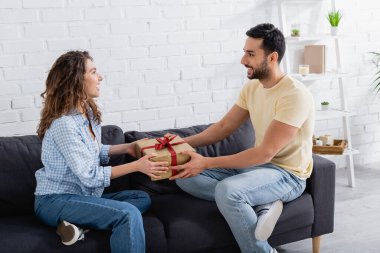 Müslüman adam, mutlu kız arkadaşına oturma odasında hediye veriyor.