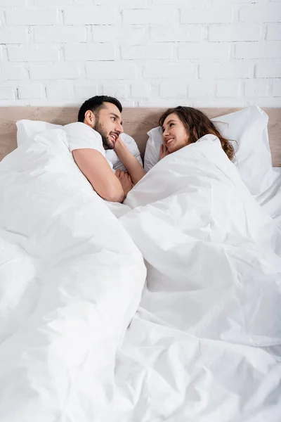 Feliz Casal Interracial Olhando Para Outro Enquanto Deitado Cama — Fotografia de Stock