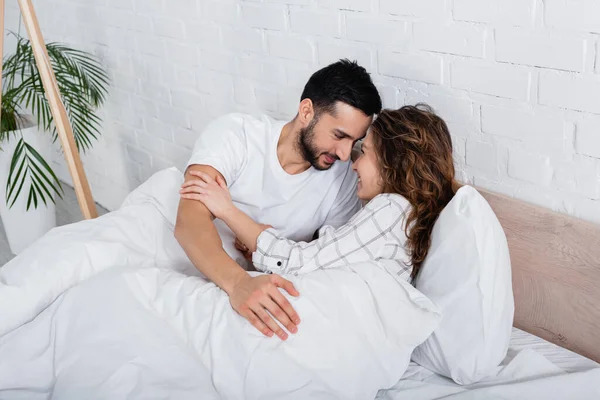 Alegre Interracial Casal Olhando Para Outro Enquanto Deitado Cama — Fotografia de Stock