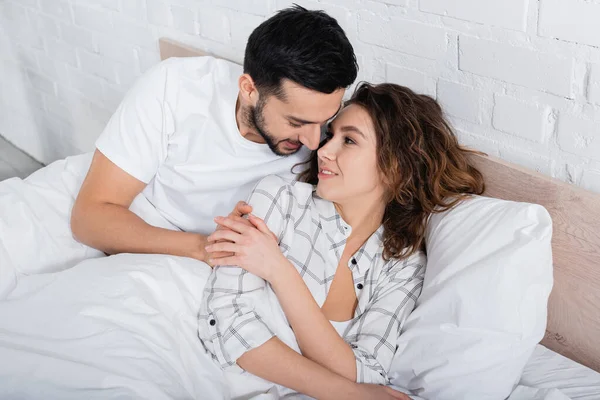 Sorrindo Casal Multiétnico Abraçando Deitado Cama — Fotografia de Stock