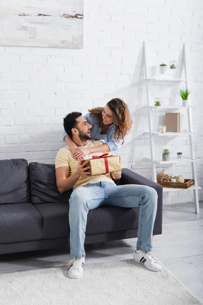 Excited Muslim Man Holding Wrapped Present Caring Girlfriend — Stock Photo, Image