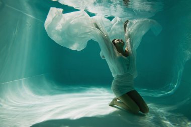 Havuzda yüzen zarif elbiseli barışçıl kadın. 