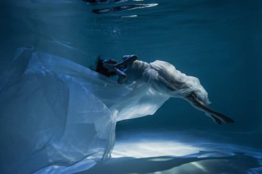 Havuzda yüzerken uyuyan beyaz şık elbiseli, huzurlu genç bir kadını aydınlatıyordu. 