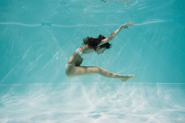 graceful young woman in swimsuit swimming in pool 