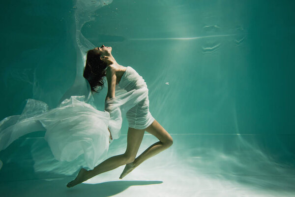 young woman in dress swimming in pool with blue water 