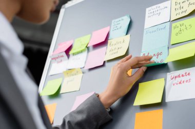 Cropped view of african american businesswoman applying sticky note on board clipart