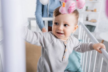 Bebek beşiğinde mutlu bir çocuk Bulanık ön planda yumuşak oyuncaklar asılı