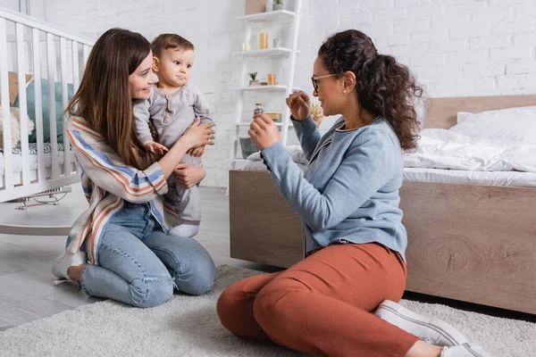 Fürsorgliche Mutter Hält Baby Neben Lächelndem Afrikanisch Amerikanischem Freund Brille — Stockfoto