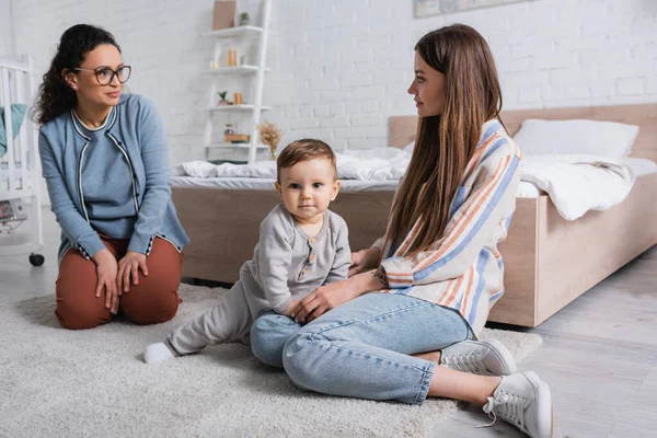 Interracial Women Looking Each Other Baby Boy Sitting Carpet — Stock Photo, Image