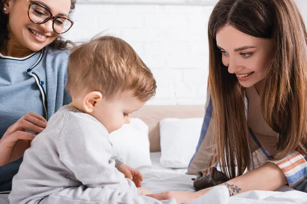 Mujeres Interracial Mirando Niño Sentado Cama — Foto de Stock