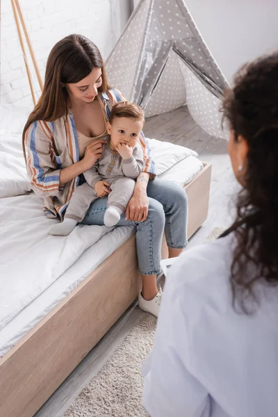 Baby Junge Sieht Afrikanisch Amerikanischen Arzt Auf Verschwommenem Hintergrund — Stockfoto