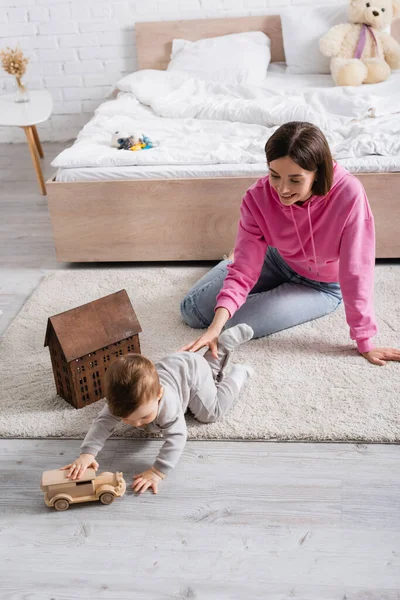 Lycklig Mor Tittar Spädbarn Son Leka Med Trä Leksak Bil — Stockfoto