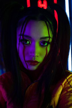 neon lighting on face of young asian woman looking at camera 