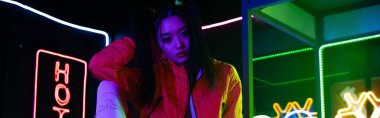 young asian woman sitting near neon sign, banner