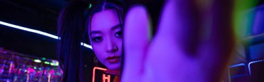 young asian woman with blurred hand near neon sign, banner 