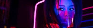 young asian woman in face shield near neon lighting, banner