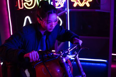 stylish young asian woman in sunglasses riding motorcycle 