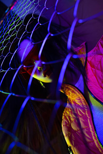 low angle view of trendy young asian woman in sunglasses looking at camera through metallic fence 