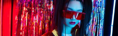 young asian woman in red sunglasses looking at camera outdoors, banner