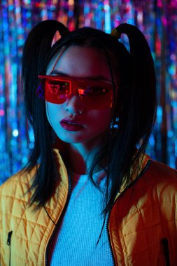 pretty asian woman in sunglasses looking at camera outside