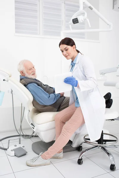 Kıdemli Hasta Diş Hekimliği Koltuğunda Yatıyor Elinde Tabletle Doktordan Konsültasyon — Stok fotoğraf