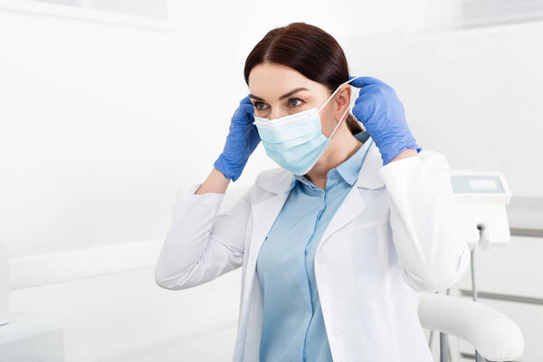 dentist in latex gloves wearing medical mask in dental clinic 