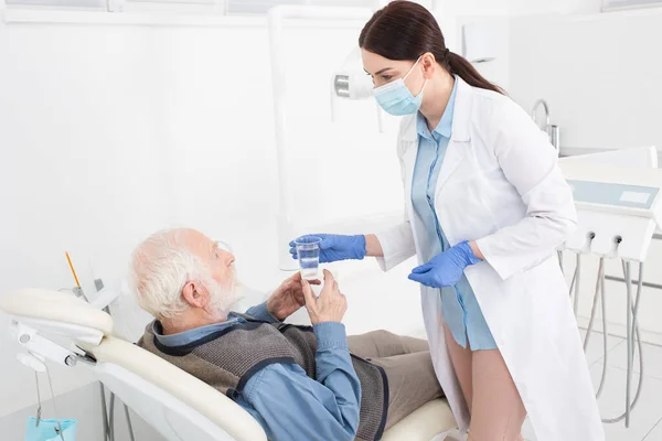 Dentiste Donnant Verre Eau Patient Âgé Allongé Sur Une Chaise — Photo