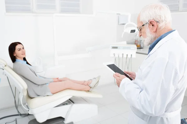 Dentista Sênior Que Consulta Paciente Sorridente Cadeira Dentária Segurando Tablet — Fotografia de Stock