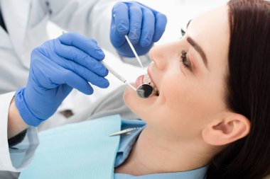 close up view of adult woman having teeth examination by doctor in latex gloves in clinic clipart