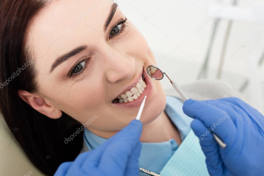 close up view of happy adult woman having teeth examination by doctor in latex gloves in clinic 