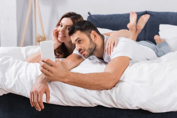 Smartphone Mão Homem Desfocado Tomando Selfie Com Namorada Cama — Fotografia de Stock