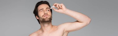 shirtless man with closed eye applying eye drops isolated on grey, banner clipart