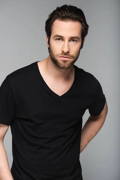 good-looking man in black t-shirt looking at camera while posing isolated on gray