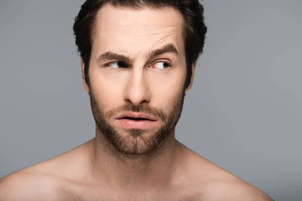 curious and good-looking man looking away isolated on grey