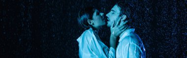 Seksi, ıslak, romantik çift, mavi renk filtresi ve pankartıyla su damlalarında nazikçe sarılıp öpüşüyor.