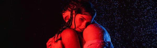wet passionate romantic couple in water drops in red and blue colors filters on black background, banner