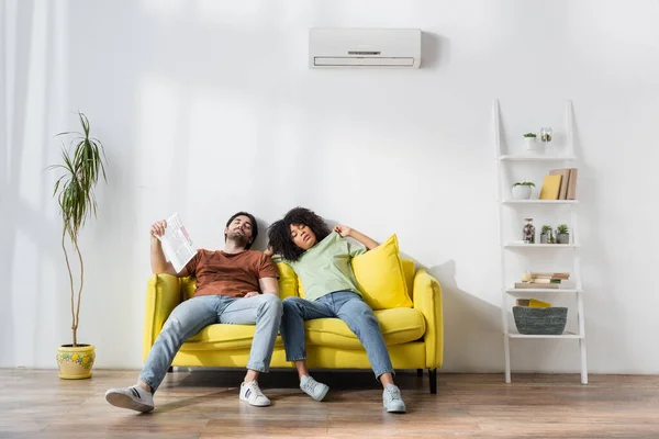 Young Man Holding Newspaper While Sitting Couch African American Girlfriend — Stock Photo, Image