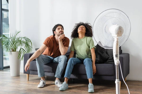 Veselý Mezirasový Muž Žena Sedí Gauči Blízkosti Rozmazané Elektrický Ventilátor — Stock fotografie