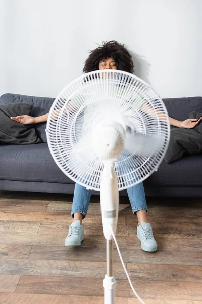 Happy African American Woman Resting Couch Blurred Electric Fan — Stock Photo, Image