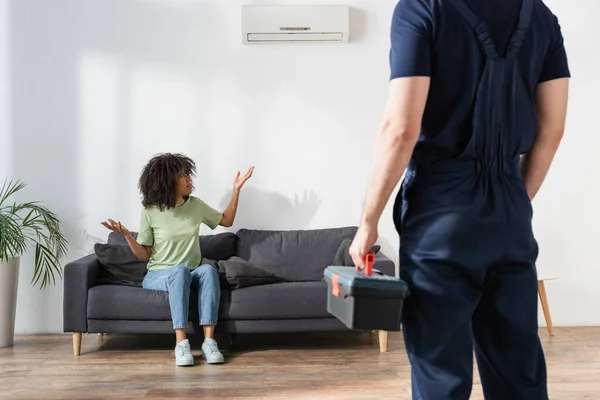 Krullend Afrikaans Amerikaanse Vrouw Kijken Naar Gebroken Airconditioner Tonen Schouderophalen — Stockfoto