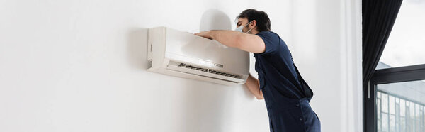 repairman in medical mask fixing air conditioner, banner
